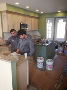 The team installing stone kitchen counter tops with custom cabinetry constructed in the Harmon Builders' cabinet workshop. Not seen in this photo are nautical-style pendant lights (over bar).