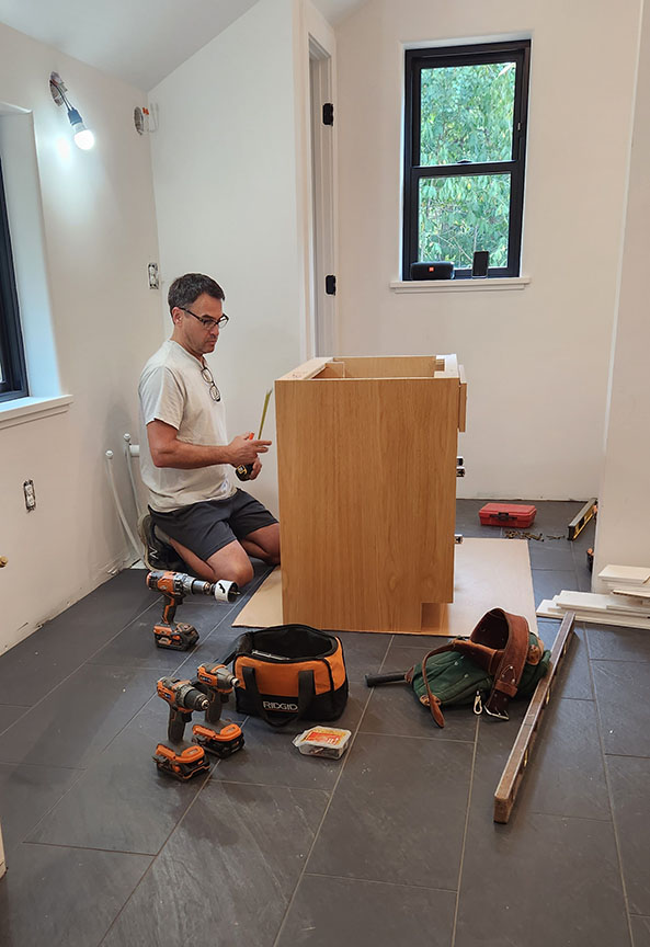 Paul Harmon measuring and installing new bathroom cabinetry