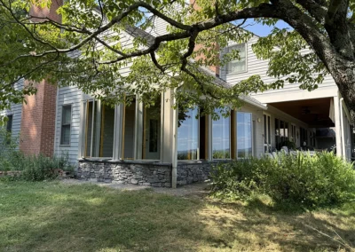Casements open for a cross-breeze. Ledgestone applied to the skirt of the sunroom to closely match other masonry on the home.