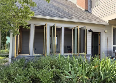 Casements open for a cross-breeze. Ledgestone applied to the skirt of the sunroom to closely match other masonry on the home.